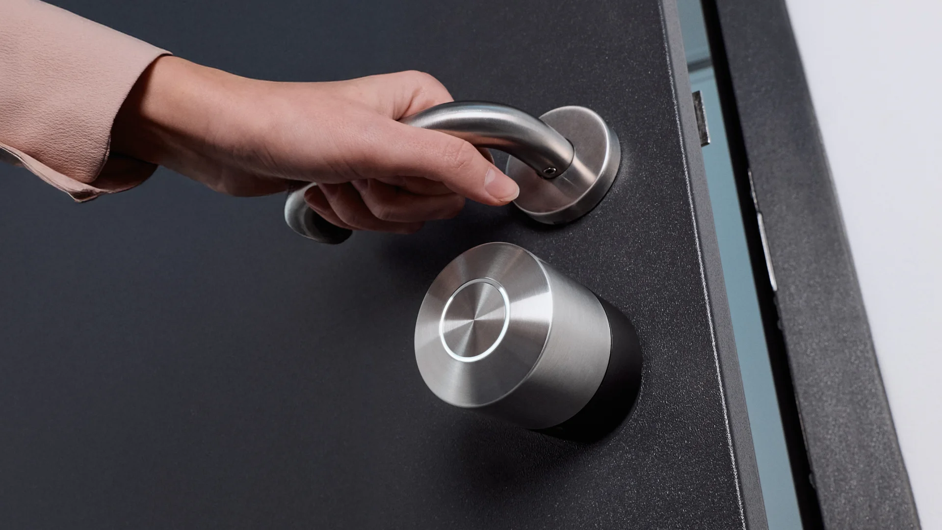 Main ouvrant une porte avec serrure connectée Nuki Smart Lock